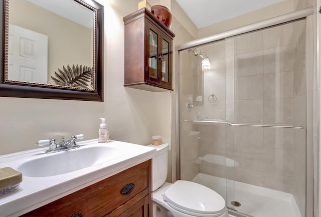 bathroom featuring vanity, toilet, and a shower with door