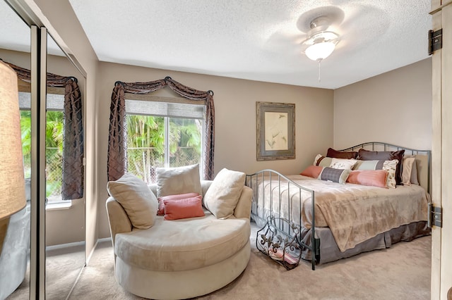 bedroom with ceiling fan, light carpet, and a textured ceiling