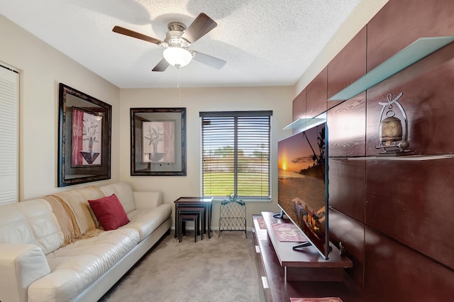 living room with light carpet, a textured ceiling, and ceiling fan