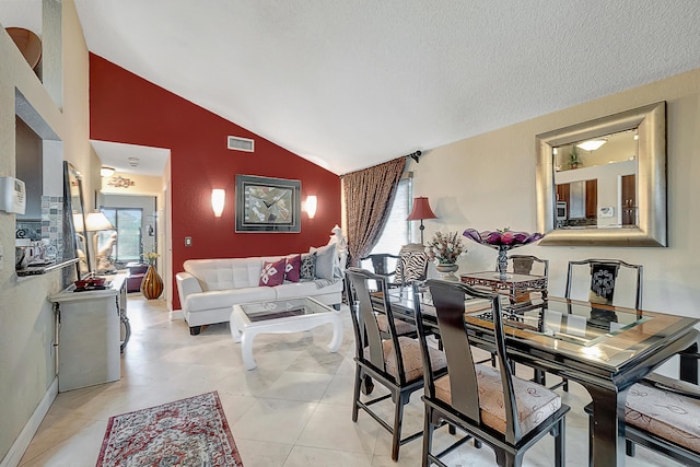 dining room featuring light tile patterned flooring, a textured ceiling, and vaulted ceiling