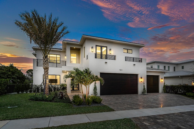 modern home with a balcony, a yard, and a garage