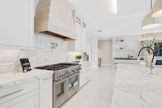 kitchen with white cabinets, double oven range, light stone counters, and custom range hood