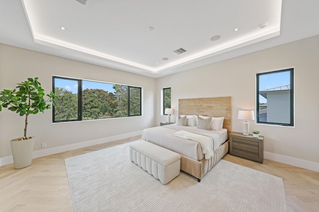 bedroom featuring light parquet floors and a tray ceiling