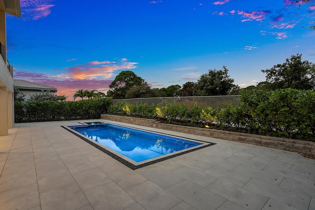 pool at dusk featuring a patio