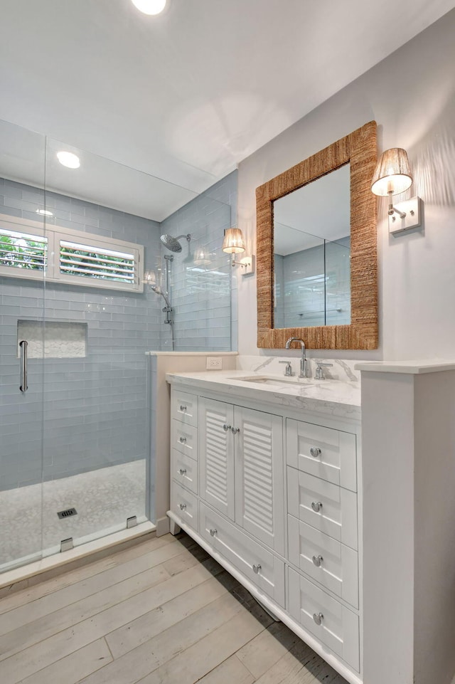 bathroom with hardwood / wood-style floors, vanity, and a shower with door