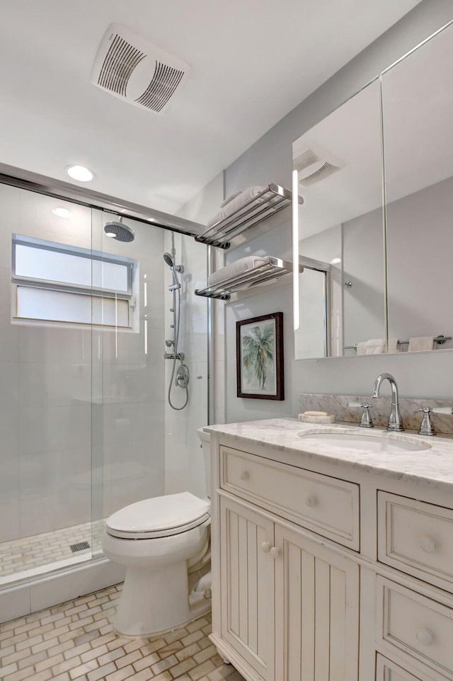 bathroom featuring vanity, toilet, and a shower with shower door