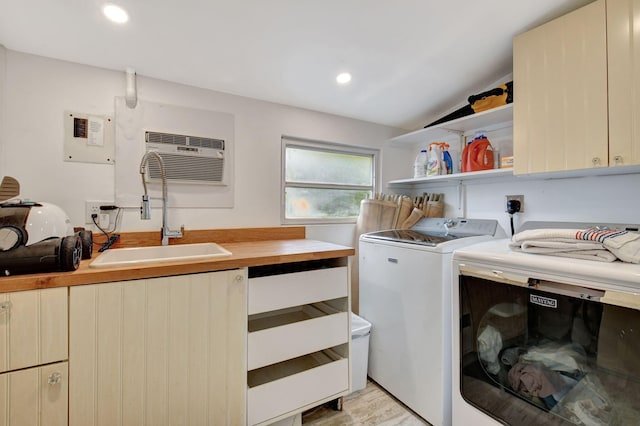 laundry room featuring cabinets, light wood-type flooring, a wall unit AC, sink, and separate washer and dryer