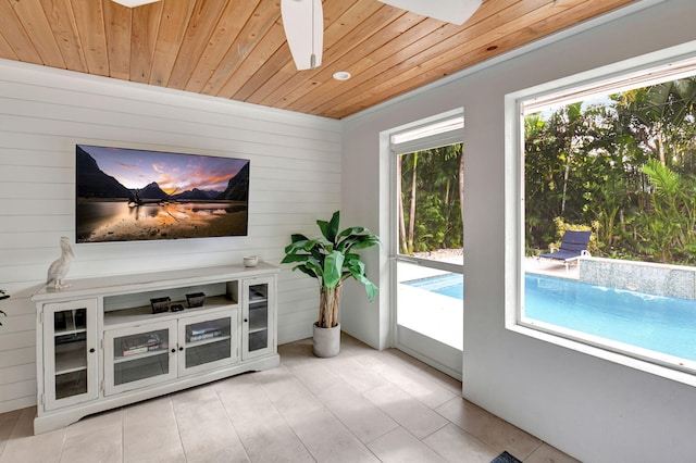 interior space featuring wooden walls, ceiling fan, wooden ceiling, and light tile patterned floors