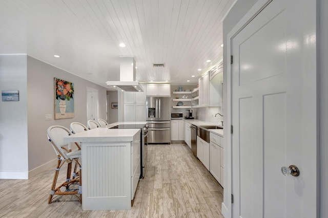 kitchen with wood ceiling, stainless steel appliances, wall chimney range hood, white cabinets, and a breakfast bar area