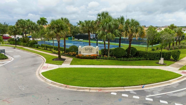 view of property's community featuring a yard and tennis court