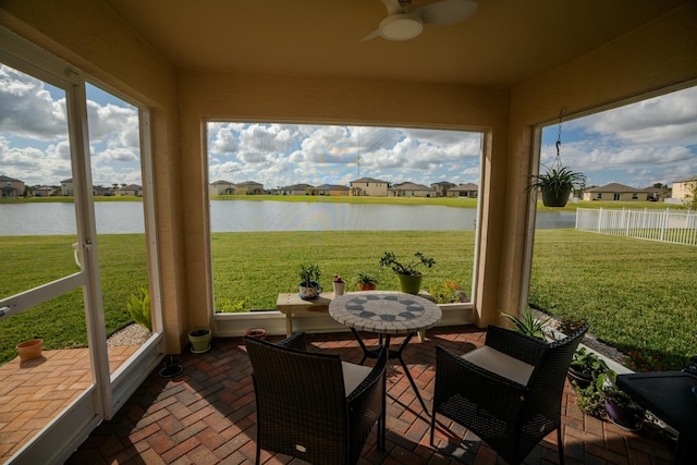 sunroom with ceiling fan and a water view