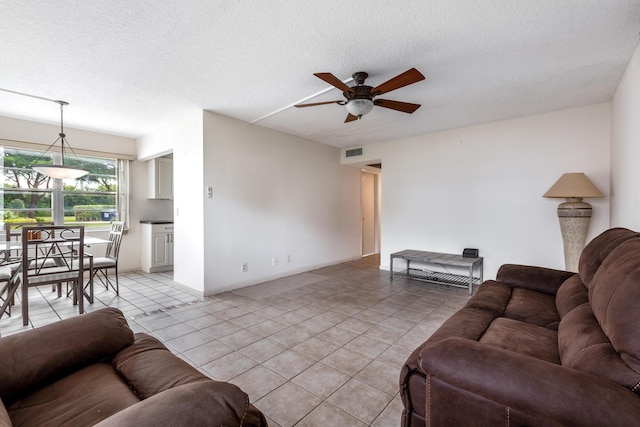 living room featuring ceiling fan, light tile patterned flooring, and a textured ceiling