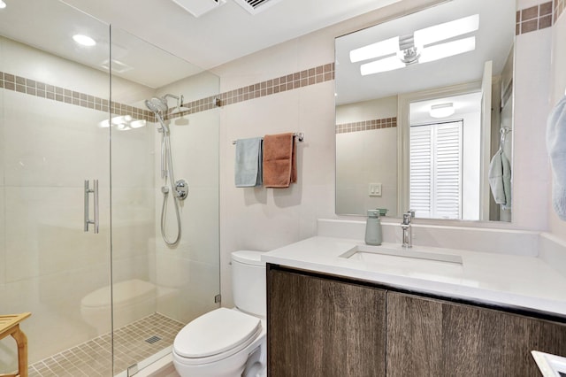 bathroom featuring vanity, toilet, walk in shower, and tile walls