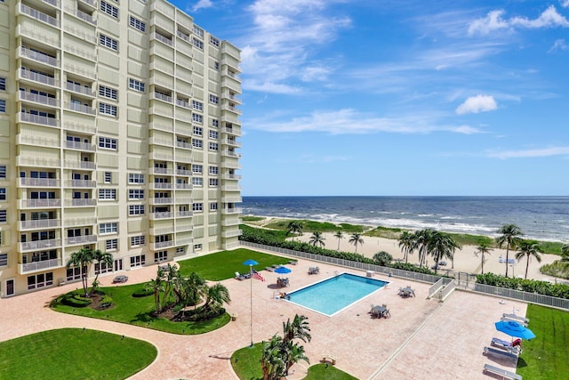 view of pool featuring a water view, a patio, and a view of the beach