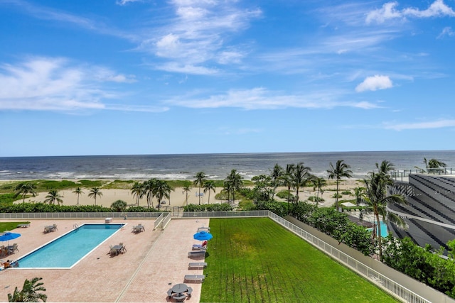 view of swimming pool with a view of the beach, a patio, a water view, and a lawn