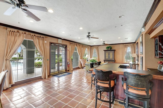 kitchen with a breakfast bar, a textured ceiling, crown molding, and tile patterned flooring