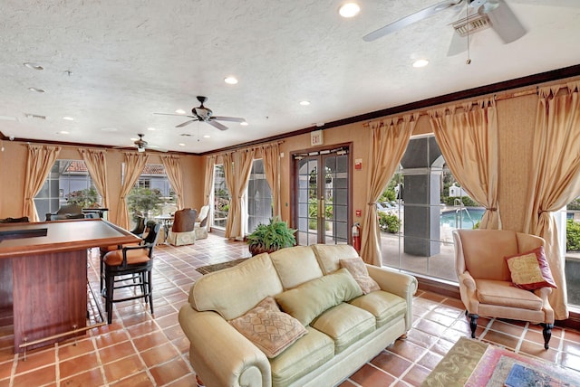 living room featuring light tile patterned floors, a textured ceiling, french doors, and crown molding