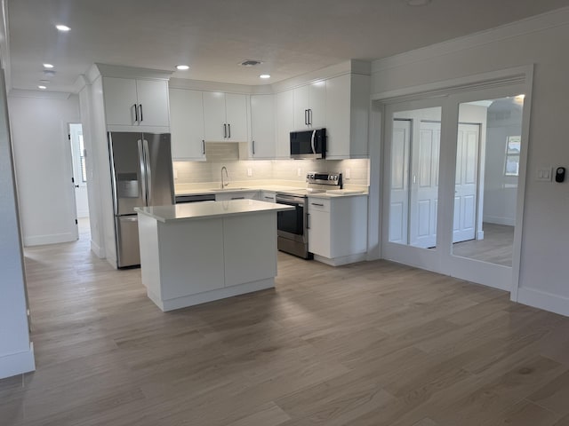 kitchen with white cabinets, light wood-type flooring, and appliances with stainless steel finishes