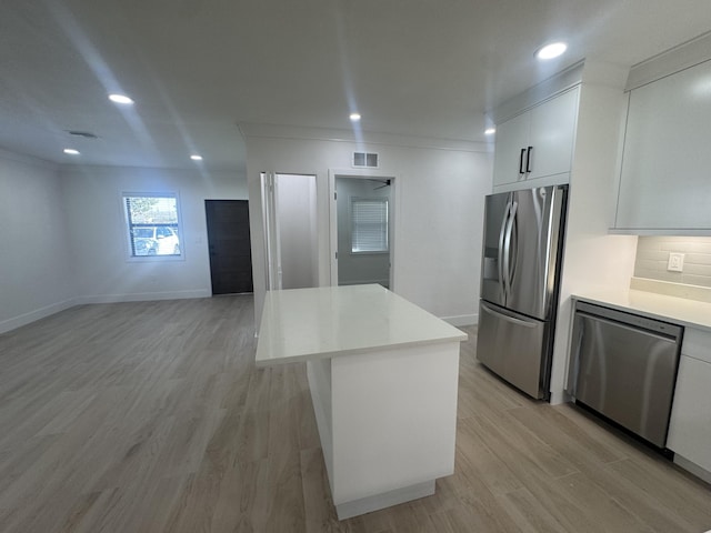 kitchen with a kitchen island, white cabinetry, appliances with stainless steel finishes, and light hardwood / wood-style flooring