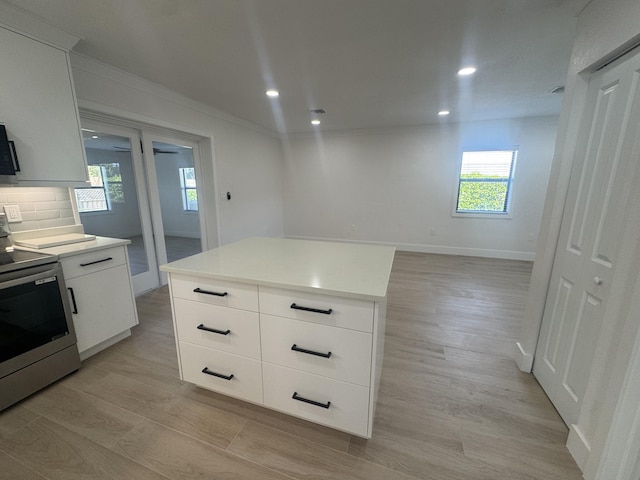 kitchen with range, a center island, white cabinetry, and a wealth of natural light