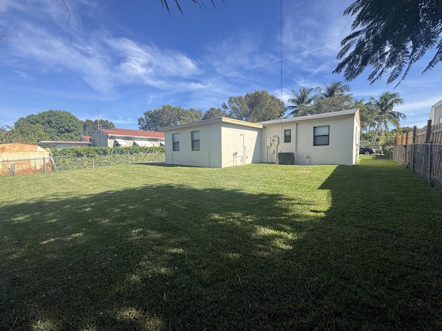 back of property featuring a yard and central AC