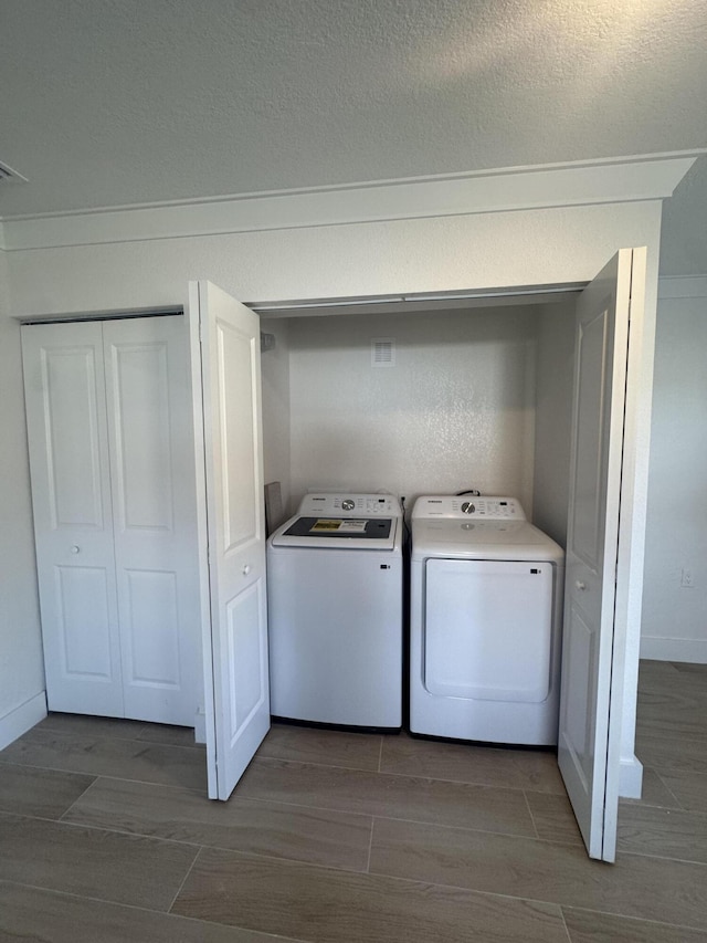 washroom with dark hardwood / wood-style flooring, independent washer and dryer, and a textured ceiling