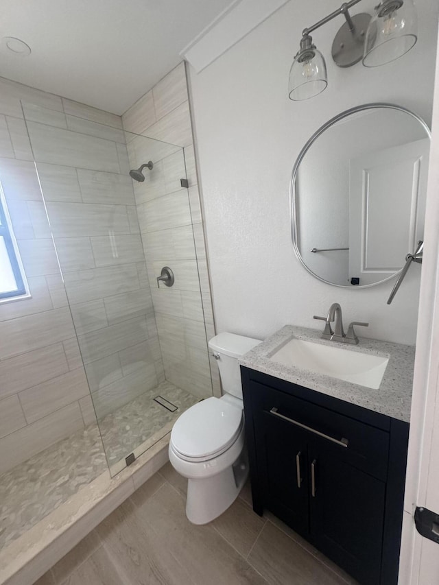 bathroom featuring a tile shower, hardwood / wood-style flooring, vanity, and toilet