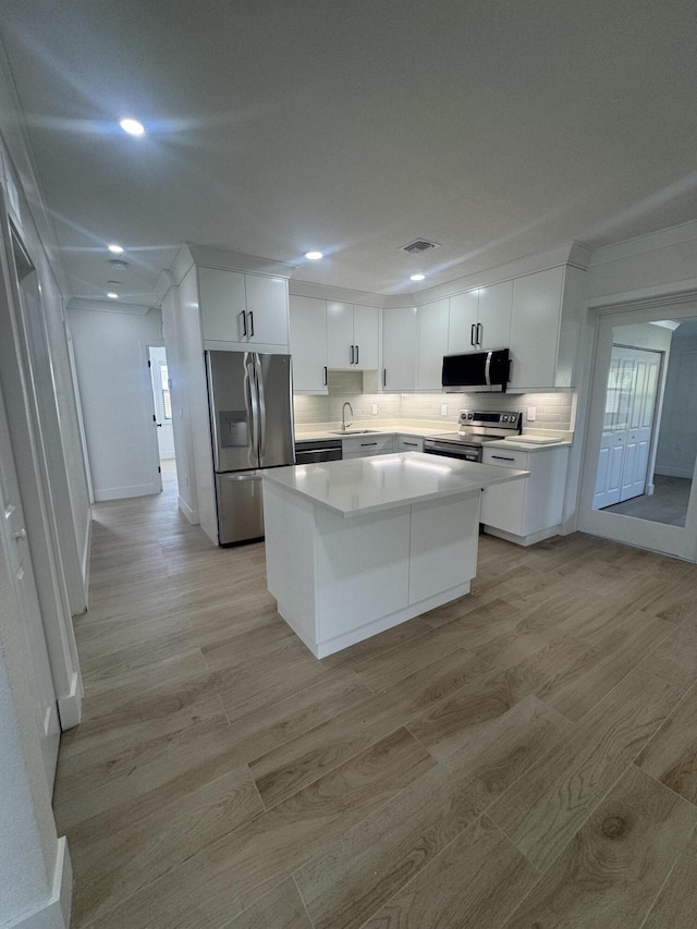 3015 Robert Rd, West Palm Beach, FL 33405 - kitchen featuring white cabinetry, appliances with stainless steel finishes, a kitchen island, and light hardwood / wood-style flooring