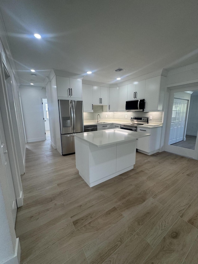 kitchen featuring sink, a center island, stainless steel appliances, light hardwood / wood-style floors, and white cabinets