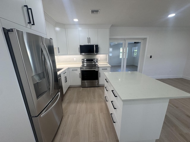 3015 Robert Rd, West Palm Beach, FL 33405 - kitchen featuring stainless steel appliances, a kitchen island, white cabinets, and decorative backsplash