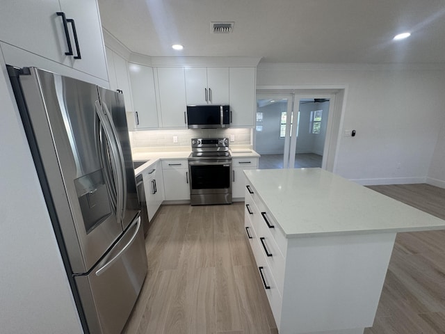 kitchen with a center island, white cabinets, light hardwood / wood-style flooring, and appliances with stainless steel finishes