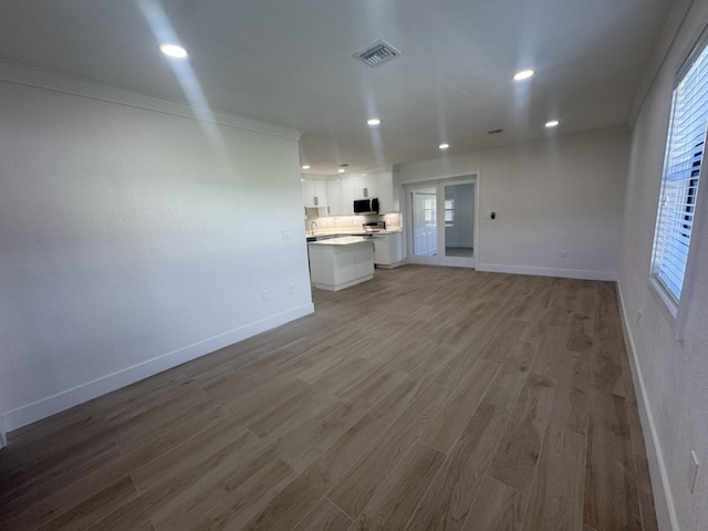 unfurnished living room with french doors, light hardwood / wood-style flooring, and crown molding