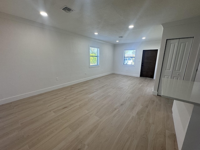 unfurnished room with light hardwood / wood-style flooring, a textured ceiling, and ornamental molding