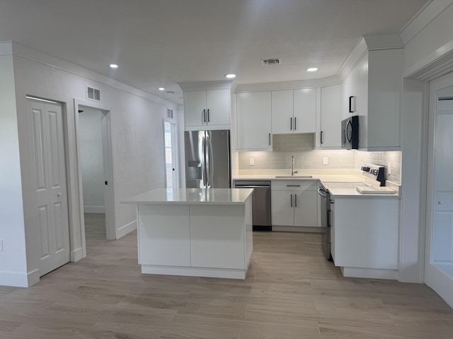 kitchen with white cabinetry, sink, decorative backsplash, appliances with stainless steel finishes, and light wood-type flooring