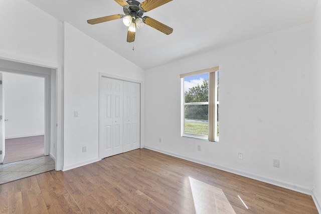 unfurnished bedroom featuring ceiling fan, a closet, wood-type flooring, and lofted ceiling