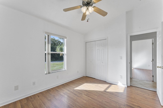 unfurnished bedroom with ceiling fan, a closet, light hardwood / wood-style floors, and vaulted ceiling