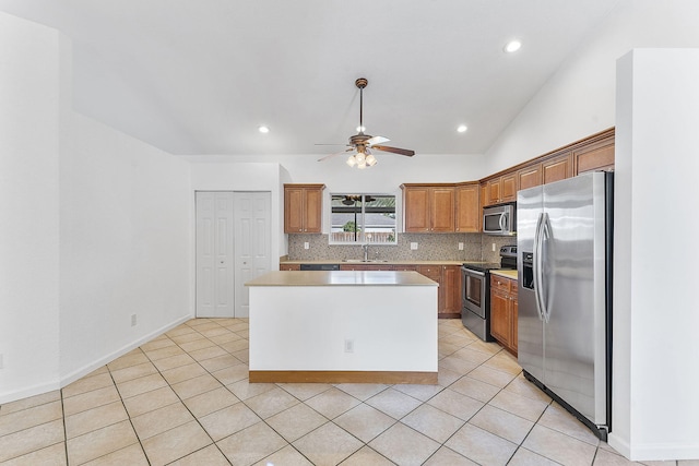 kitchen featuring ceiling fan, backsplash, vaulted ceiling, a kitchen island, and appliances with stainless steel finishes