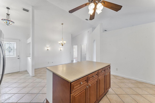 kitchen featuring a center island, ceiling fan with notable chandelier, hanging light fixtures, vaulted ceiling, and light tile patterned floors