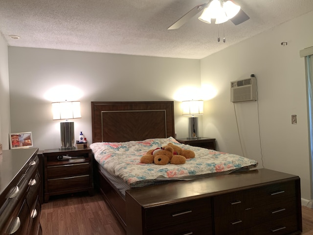 bedroom featuring dark hardwood / wood-style floors, ceiling fan, an AC wall unit, and a textured ceiling