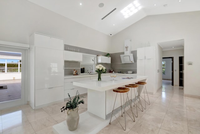 kitchen featuring a kitchen breakfast bar, a center island, white cabinetry, and backsplash