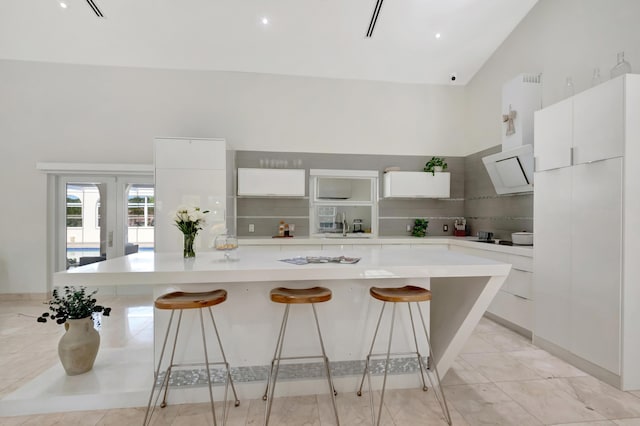 kitchen with white cabinets, a kitchen breakfast bar, a spacious island, and french doors