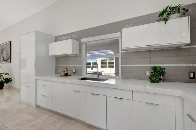 kitchen with decorative backsplash, white cabinetry, and sink