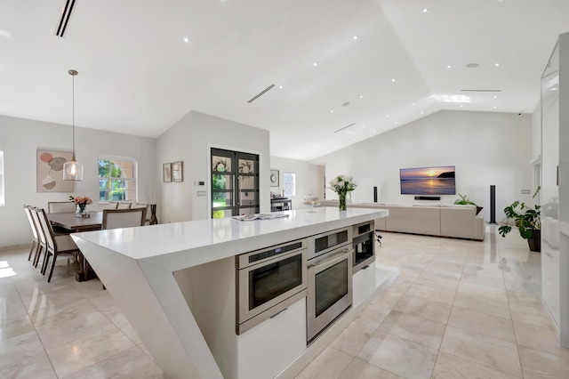 kitchen with white cabinetry, hanging light fixtures, lofted ceiling, and a large island