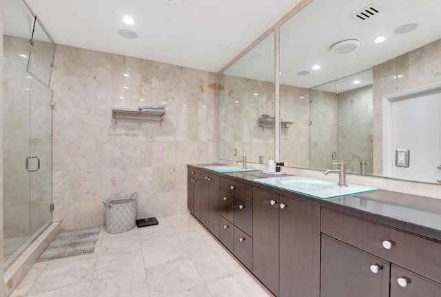 bathroom featuring tile patterned flooring, vanity, a shower with door, and tile walls