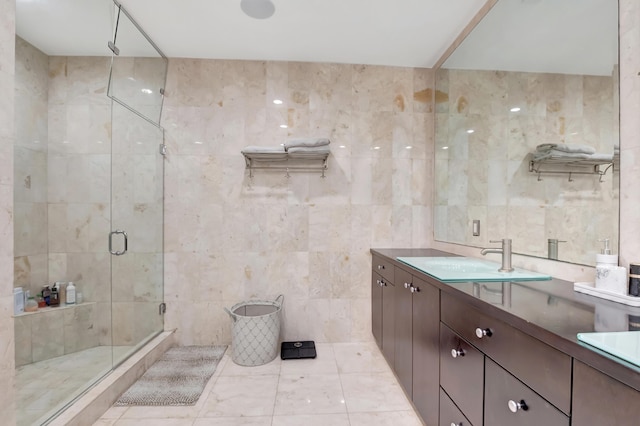 bathroom with vanity, a shower with door, and tile walls