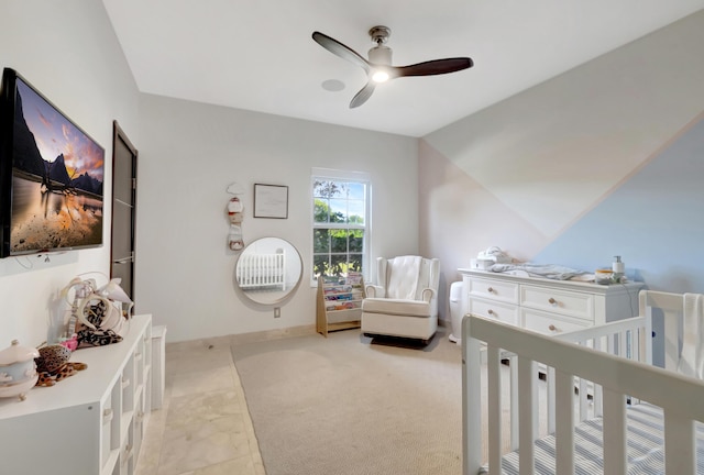 bedroom with ceiling fan, a nursery area, and lofted ceiling