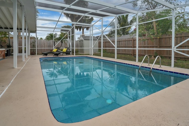 view of swimming pool with glass enclosure, a patio area, and a storage shed