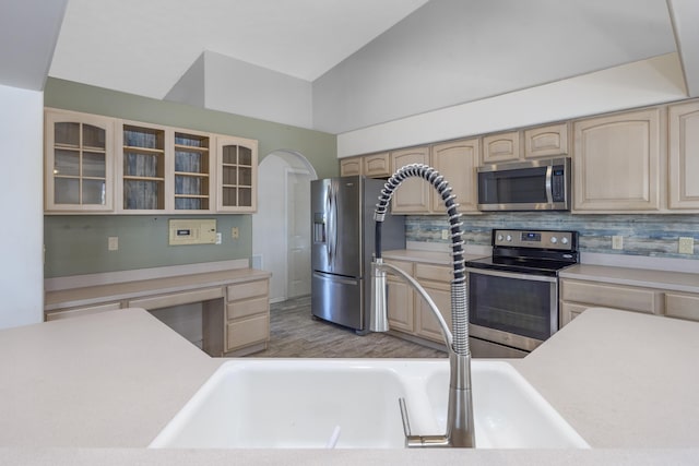 kitchen with appliances with stainless steel finishes, light brown cabinetry, tasteful backsplash, wood-type flooring, and lofted ceiling