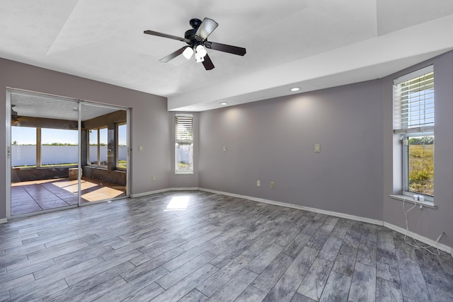 spare room featuring hardwood / wood-style floors, ceiling fan, and a healthy amount of sunlight