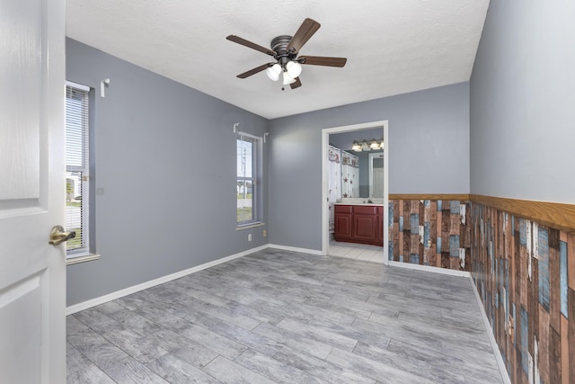 spare room featuring ceiling fan, light wood-type flooring, and a textured ceiling